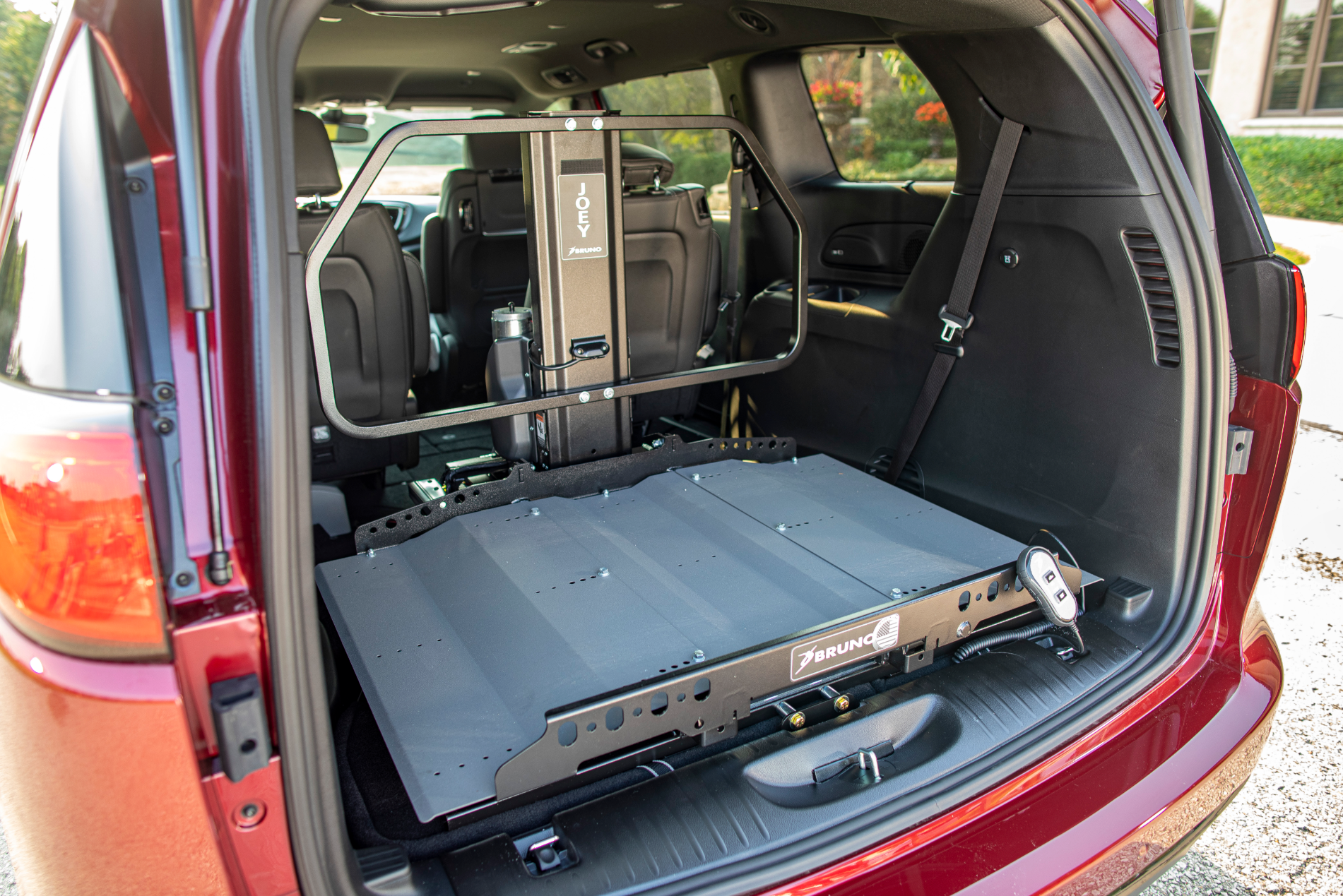 The back of a red minivan with a automobile lift by Altamira Ltd. in the back.