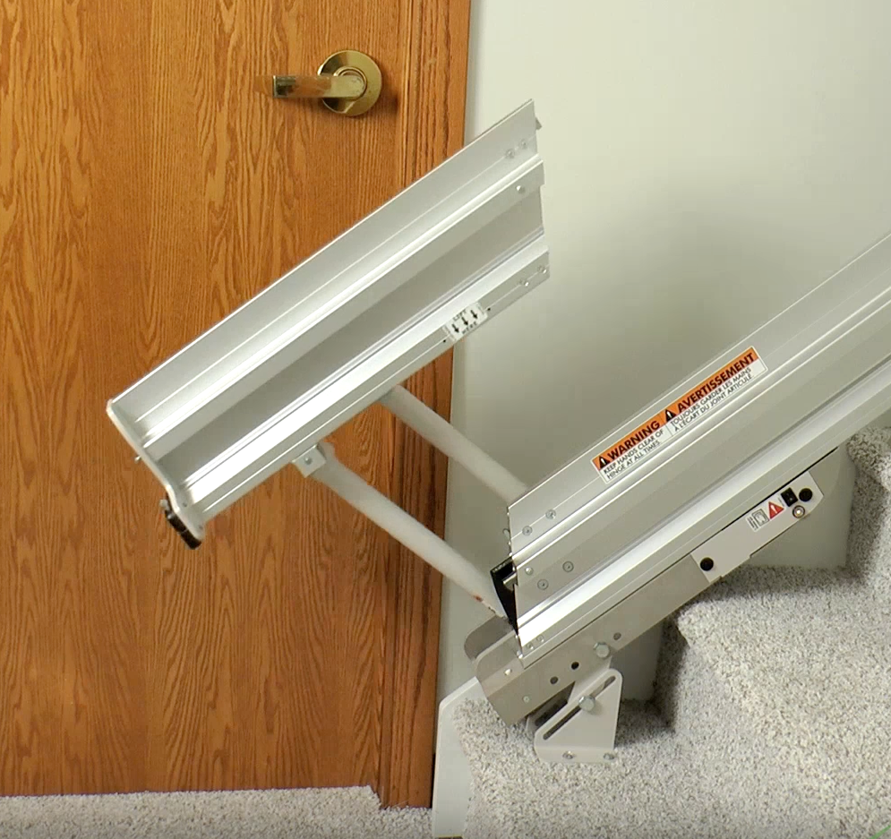 A bruno stair lift is sitting on the stairs in a living room next to a couch installed by Altamira ltd.