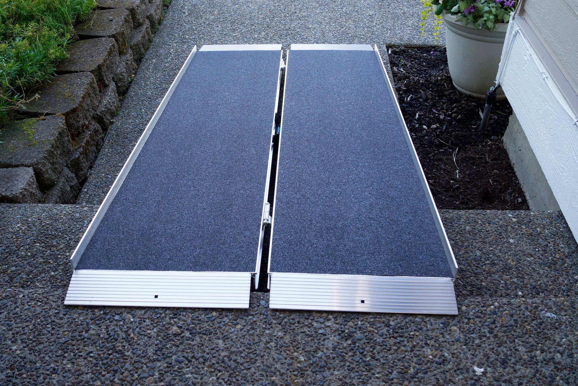 A ramp is sitting on a sidewalk next to a potted plant