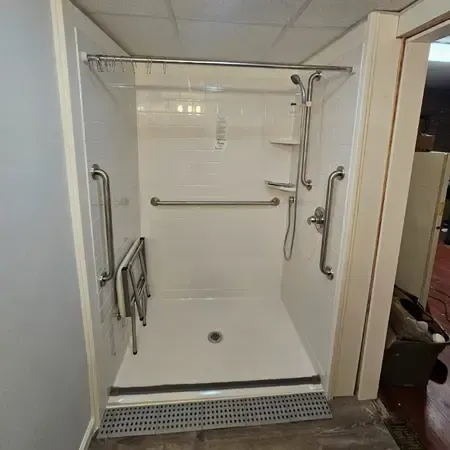 An accessible bathroom with a walk in shower by Altamira Ltd.