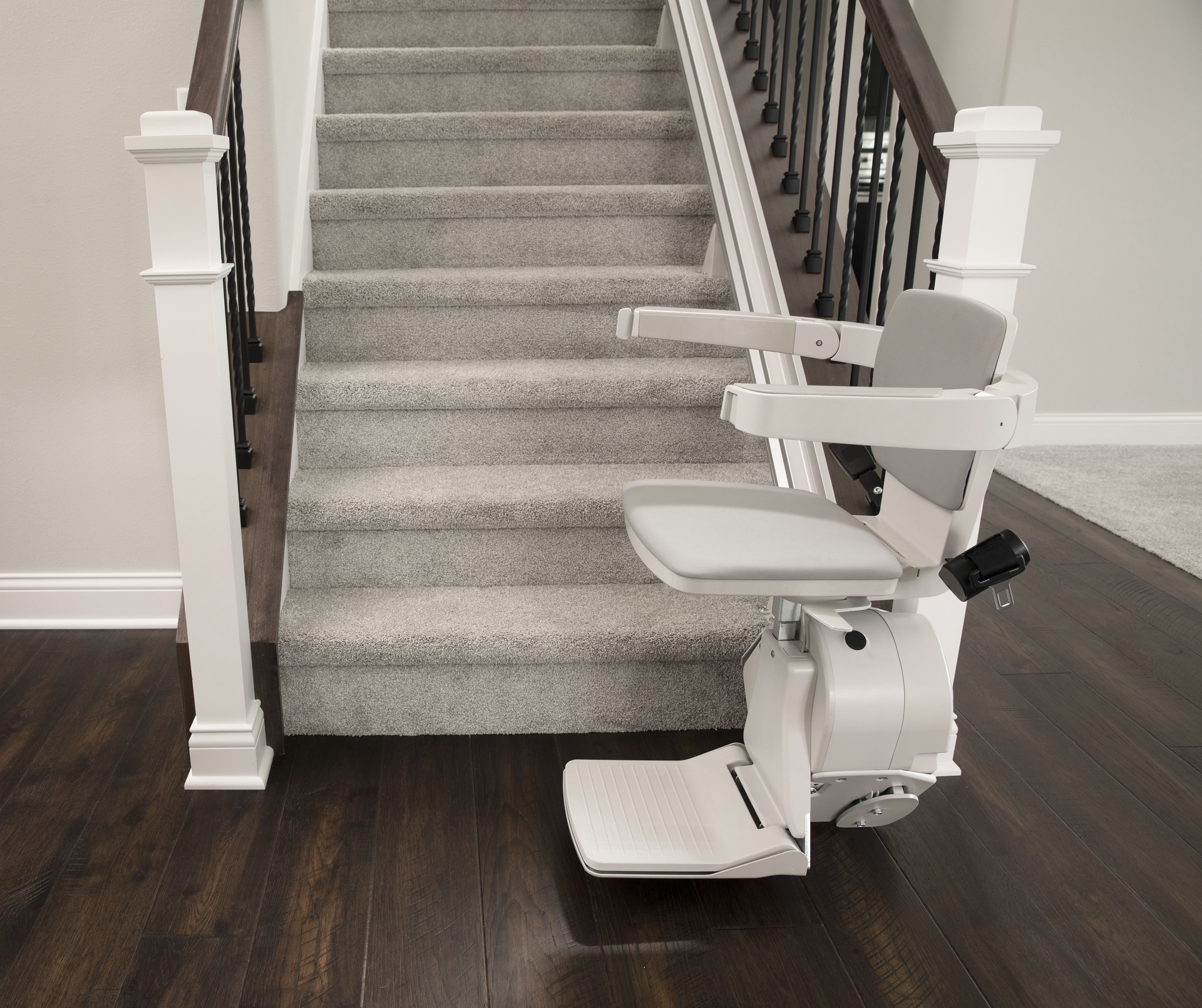 A stair lift installed by Altamira Ltd. is sitting on the bottom of a set of stairs