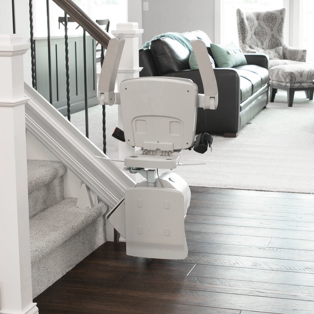 A bruno Elan stair lift in a living room next to a couch installed by Altamira Ltd. 