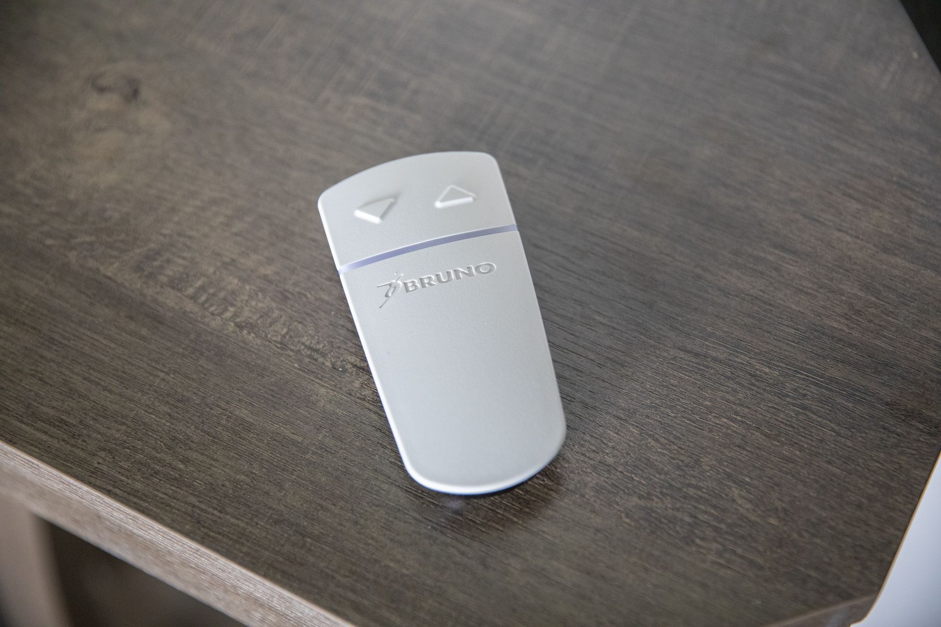A white remote control for a stairlift is sitting on a wooden table.