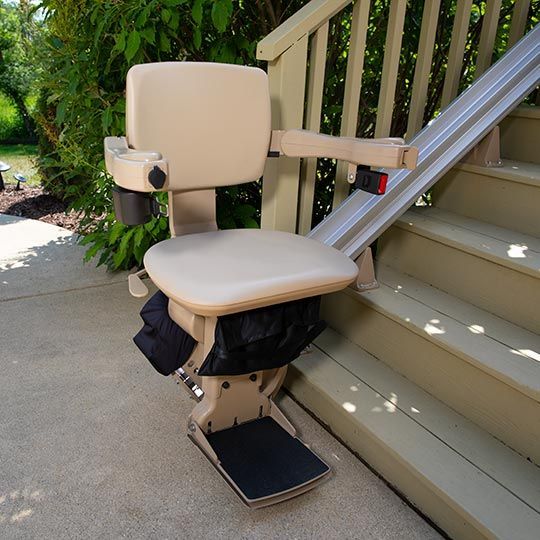 A straight stair lift by Altamira Ltd.  is sitting on the side of a set of stairs