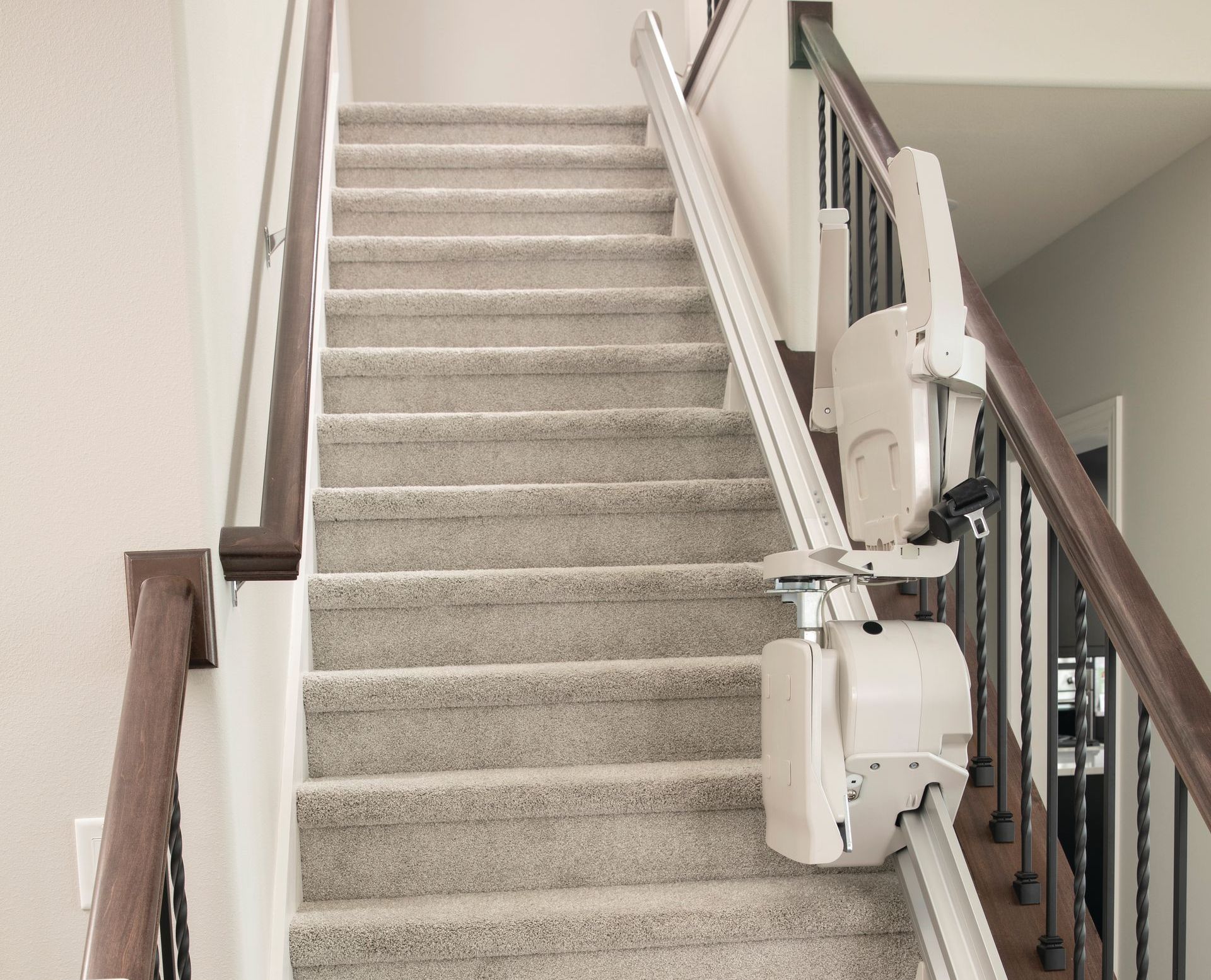 A stair lift is attached to the side of a set of stairs.