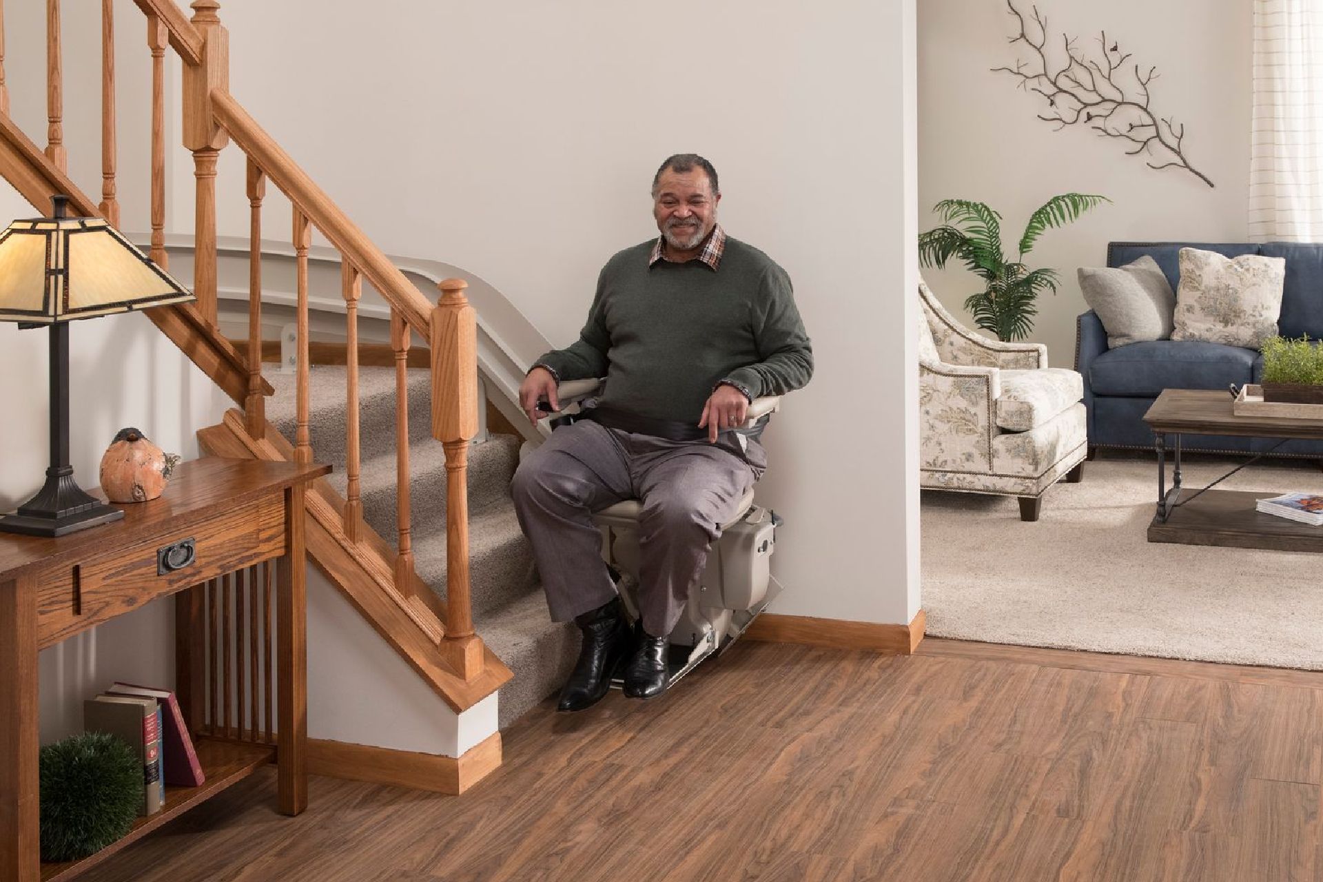 A man is sitting on a bruno stair lift installed by Altamira Ltd.