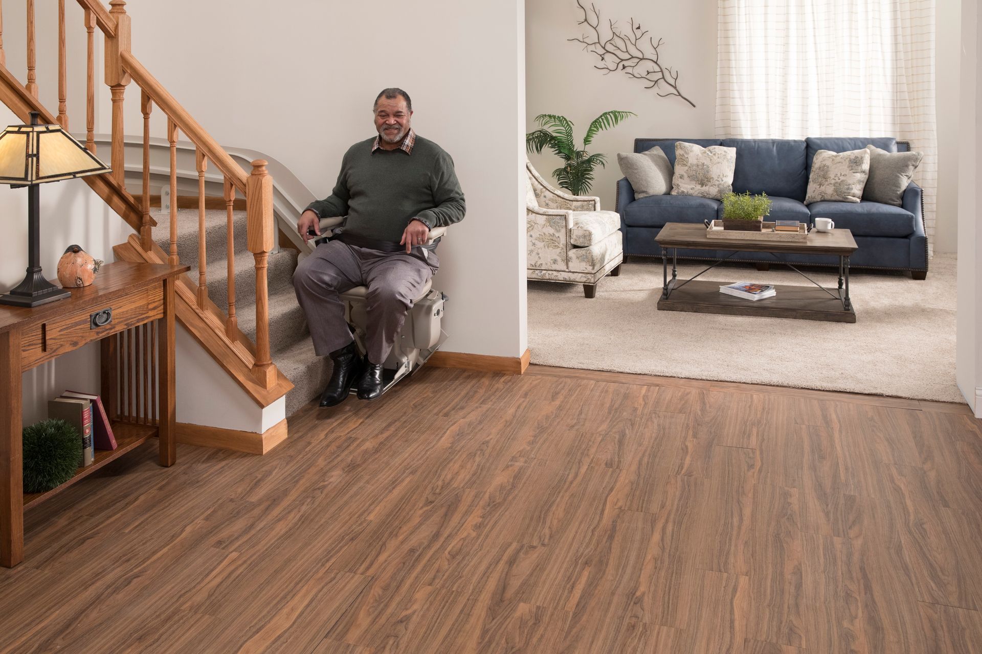 A man in a wheelchair is sitting on a stair lift in a living room.
