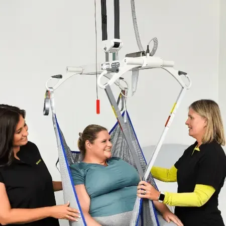 A woman is being lifted in a patient lift installed by Altamira Ltd.