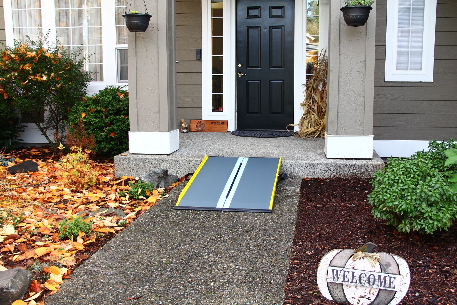 A welcome sign is on the sidewalk in front of a house