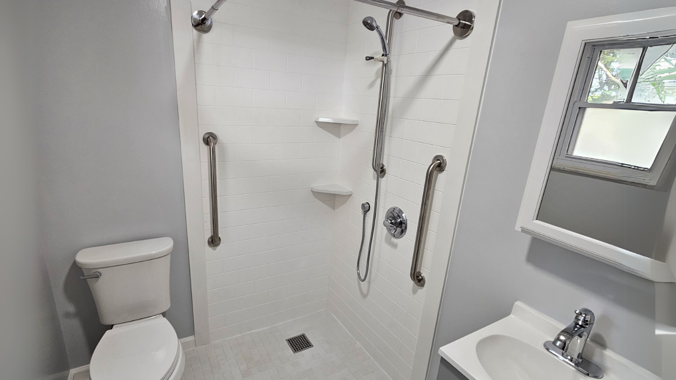 An accessible bathroom modification by Altamira Ltd. with a toilet , sink and shower.