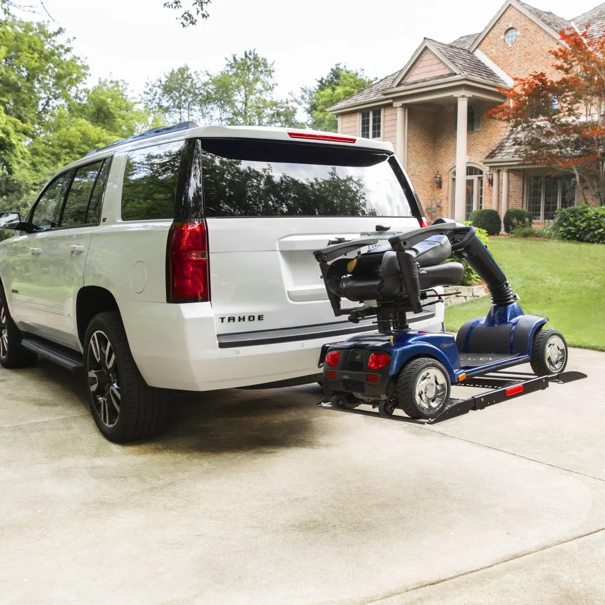 A Bruno automobile lift carrying a scooter on a white SUV.