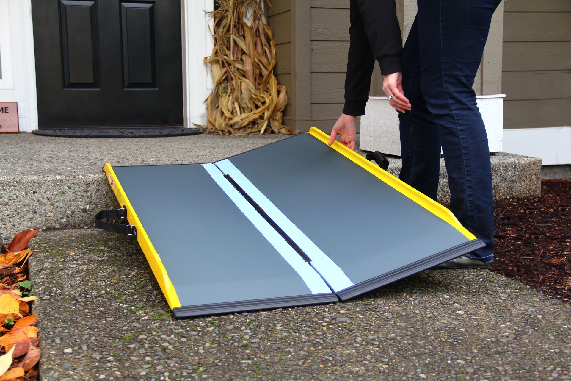 A person is standing next to a folding ramp in front of a house.