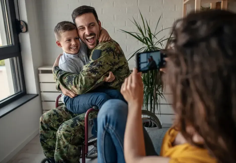 A woman is taking a picture of a soldier and his son.