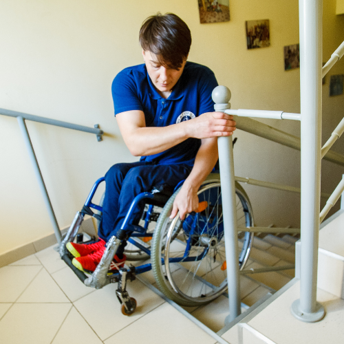 A man in a wheelchair is sitting in front of stairs.