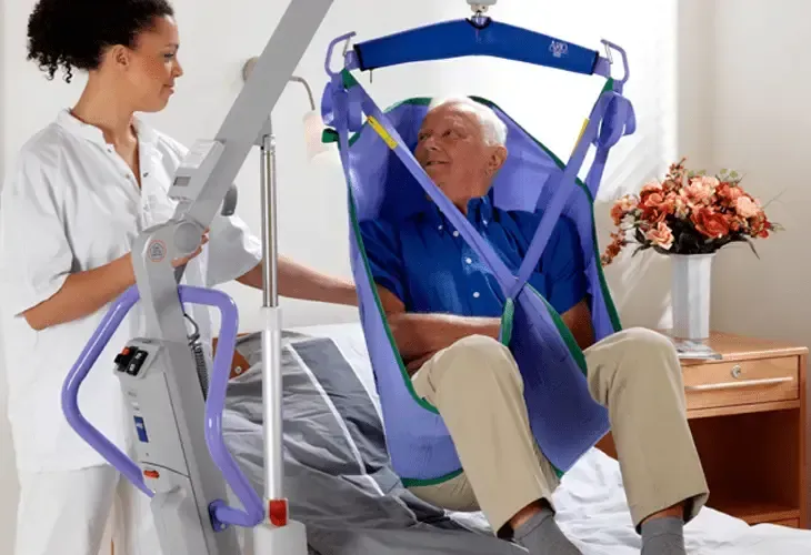 A man is being lifted in a sling by a nurse using a patient lift by Altamira Ltd.