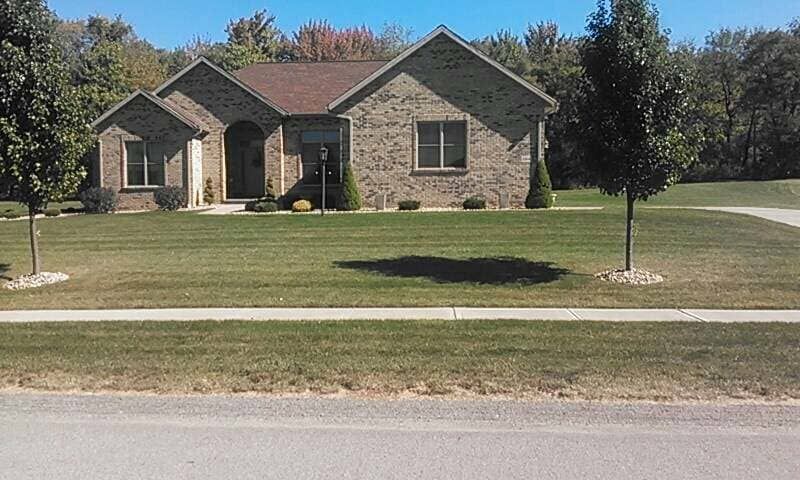 A brick house with a lush green lawn in front of it