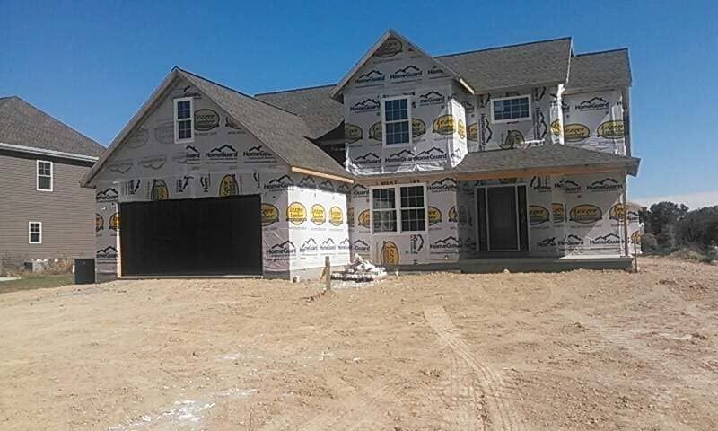A large house is being built in the middle of a dirt field.