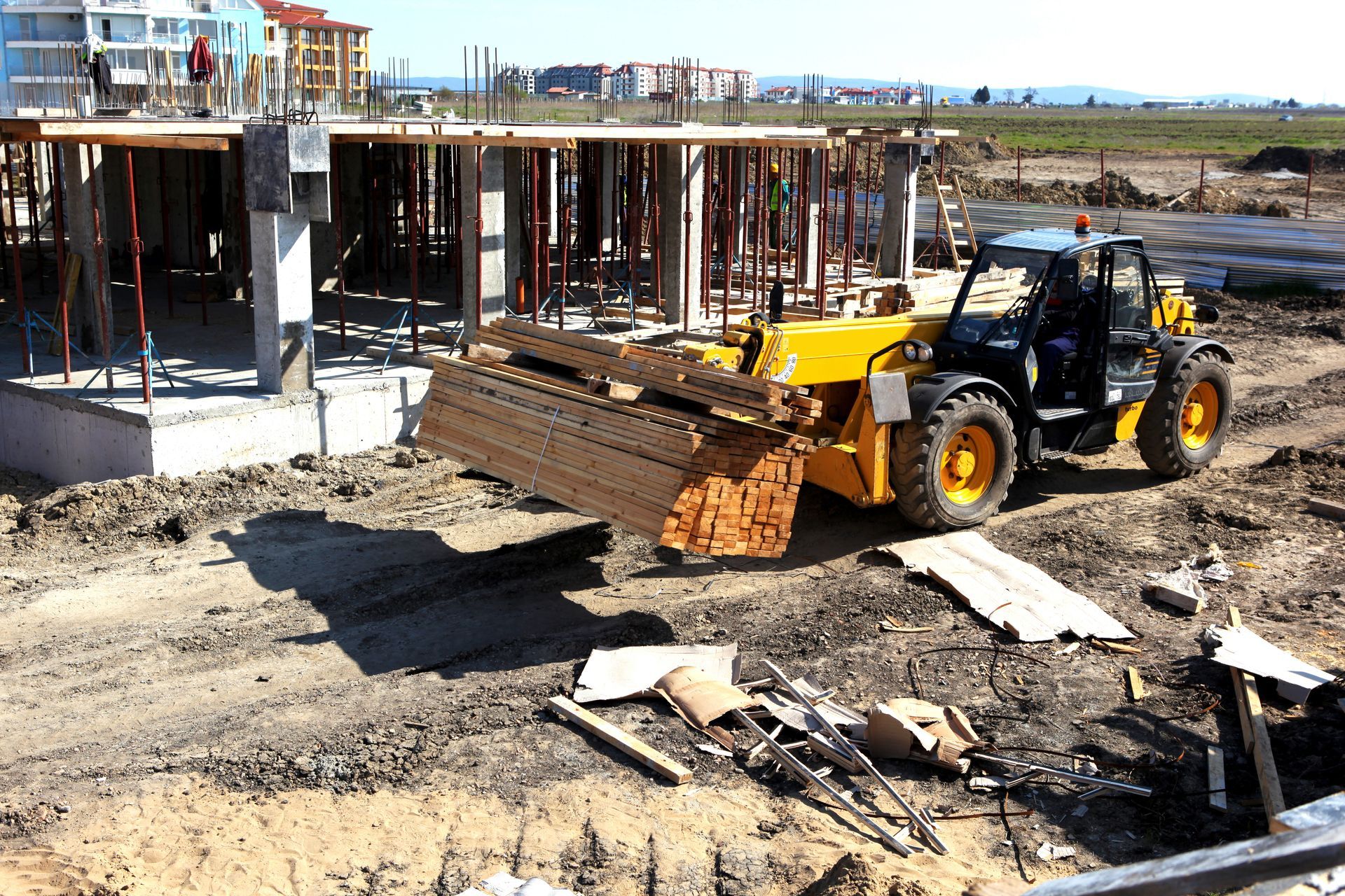A home construction site with a loader carrying plywood. A home construction site with a loader carrying plywood.