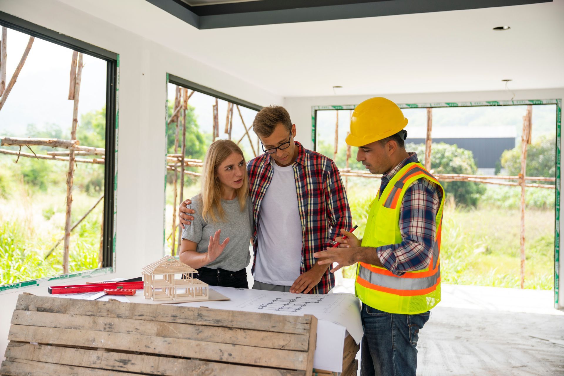 Husband and wife consulting with a architect inside a home under construction.
