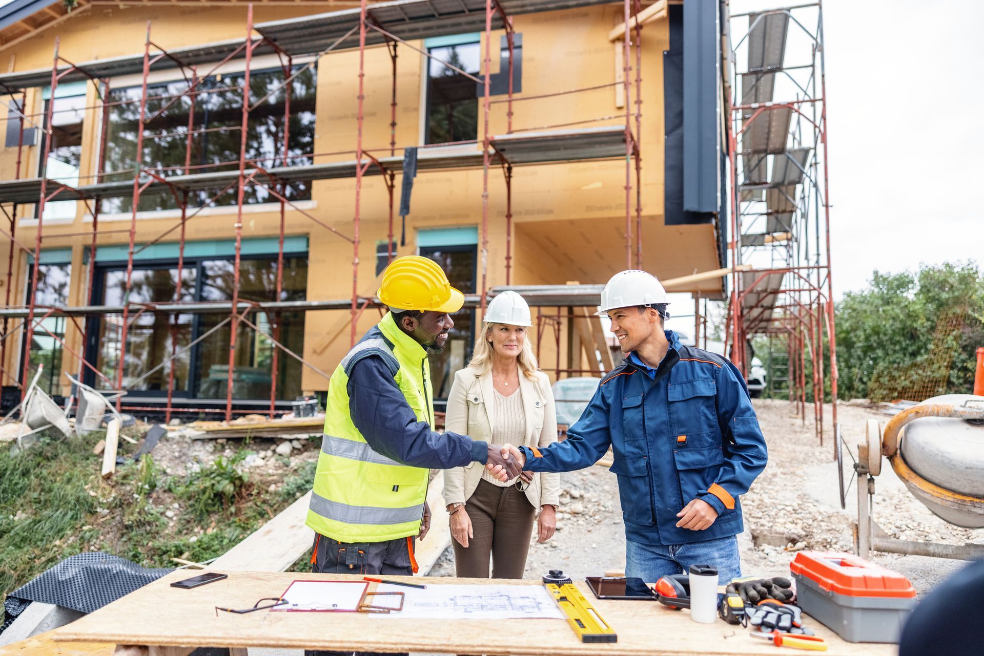 A home building contractor shaking hands with construction workers at a home builder company.