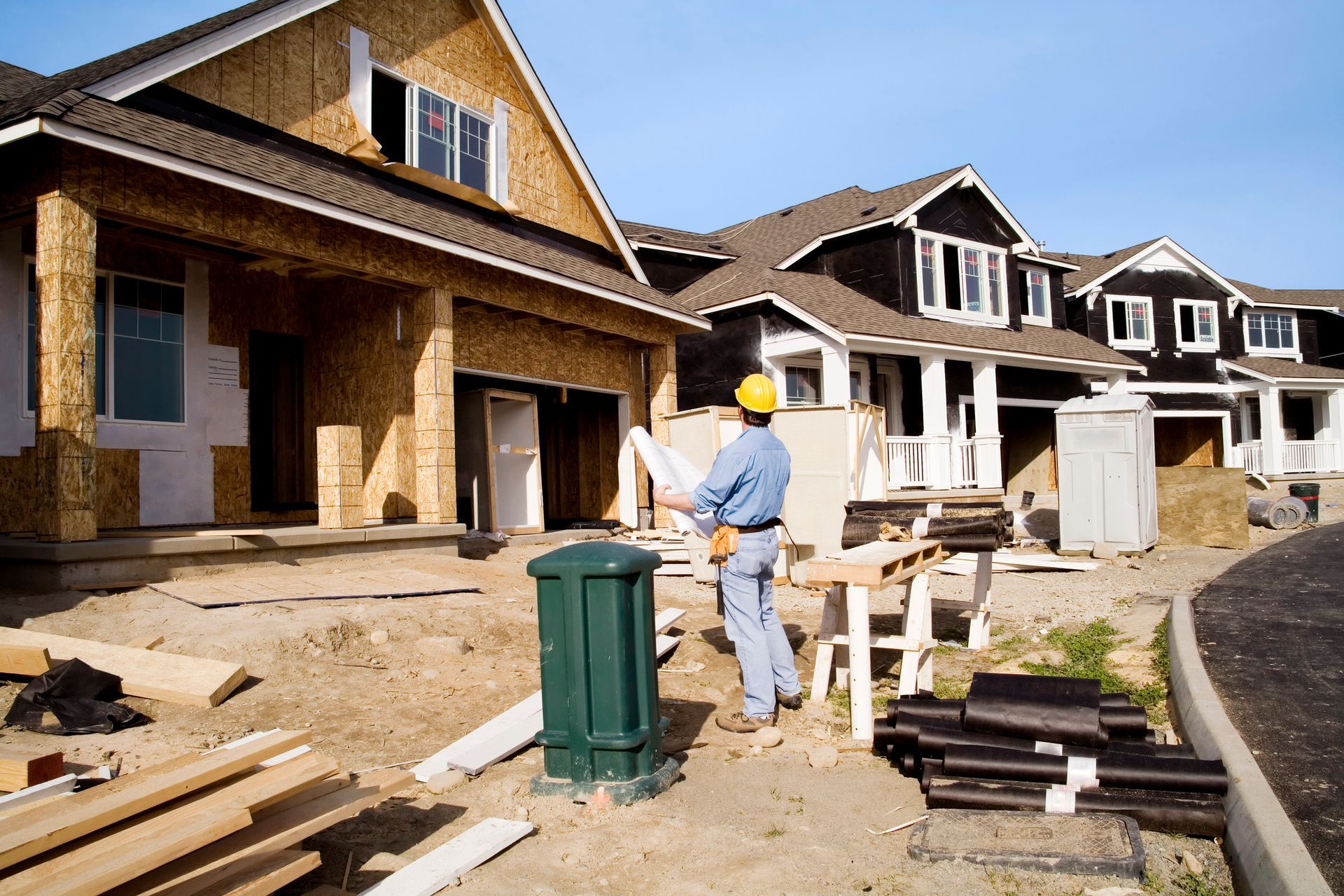 Construction worker examining plans at a residential housing development site.