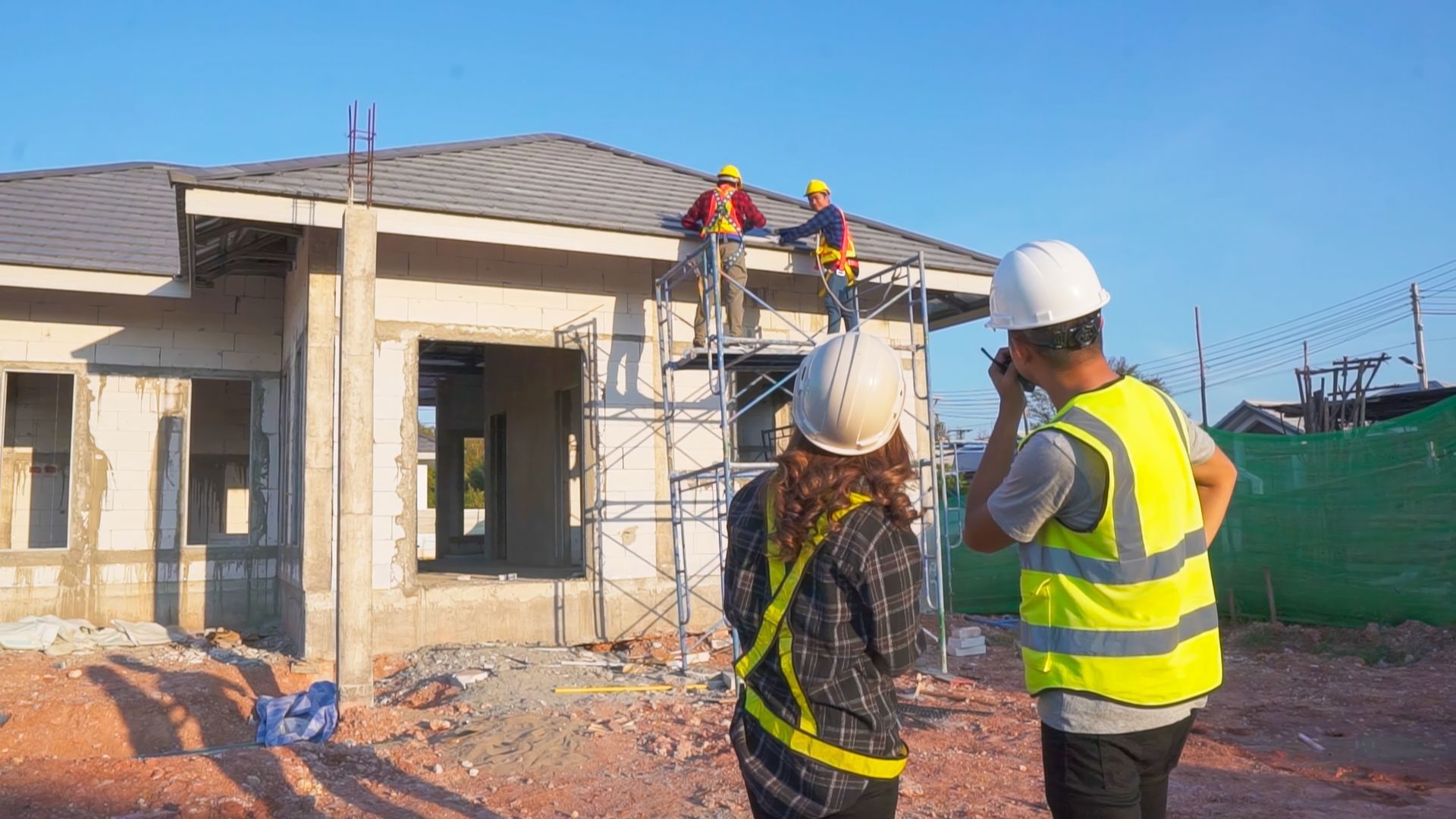 Engineer and architect using radios to coordinate at a residential construction site.