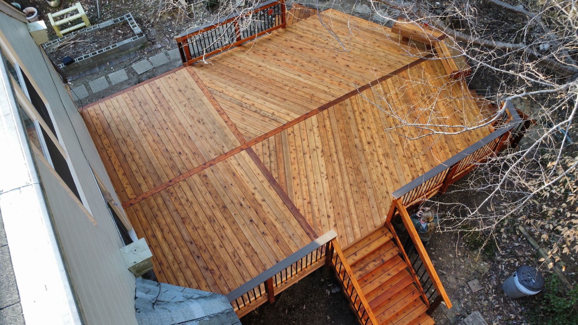 Wooden deck with stairs, railing, and a geometric pattern.