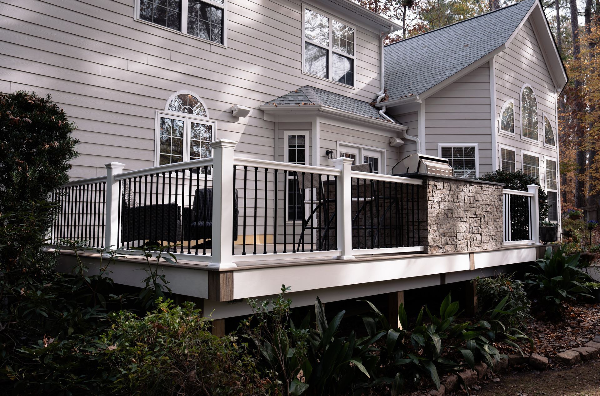 Back of a two-story light gray house with a deck. The deck has white rail