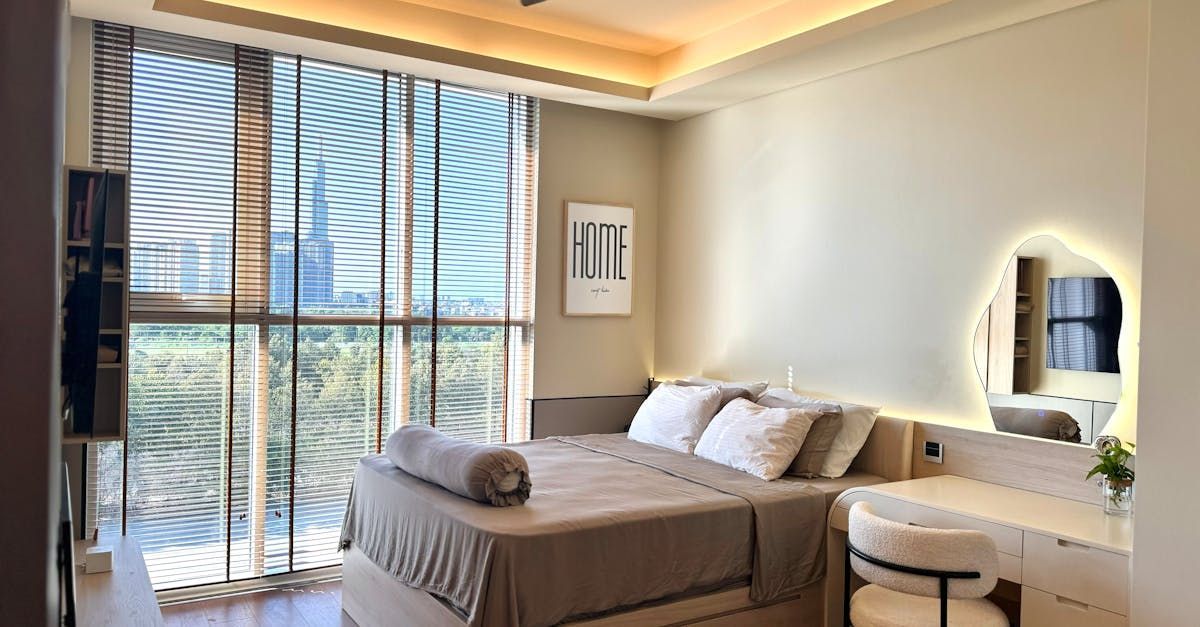 A bedroom with a bed , dresser , mirror and large windows.
