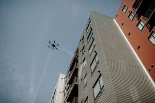 A drone is flying in the sky above a building.