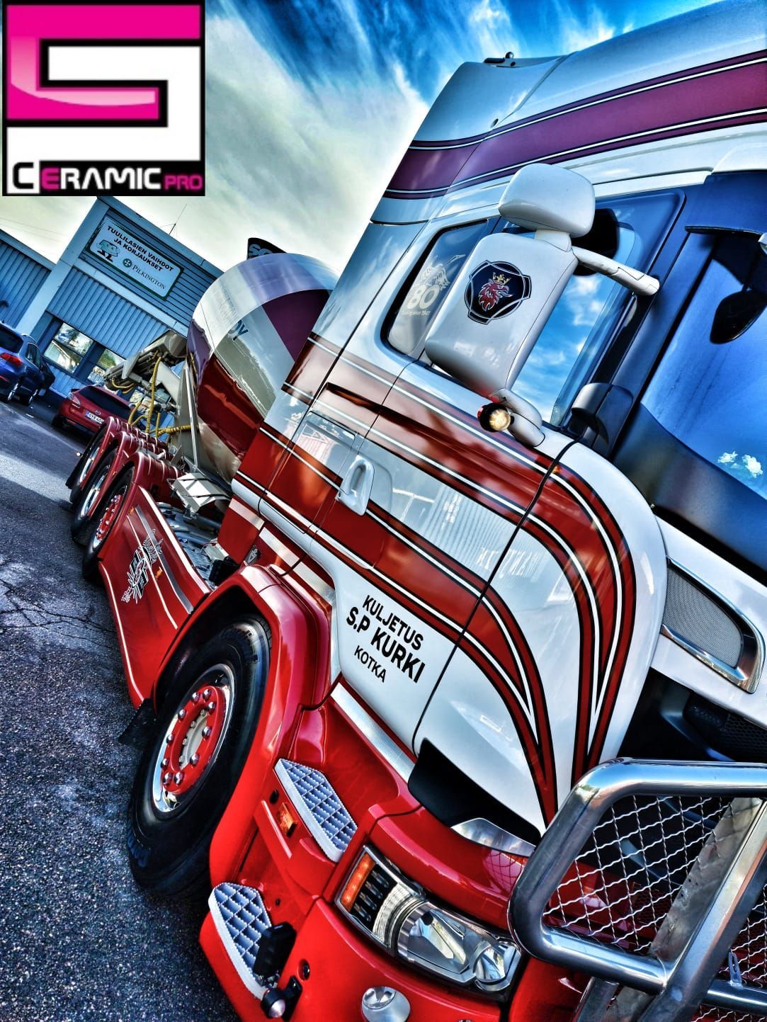 Punainen ja valkoinen kuorma-auto on pysäköity toisen kuorma-auton viereen