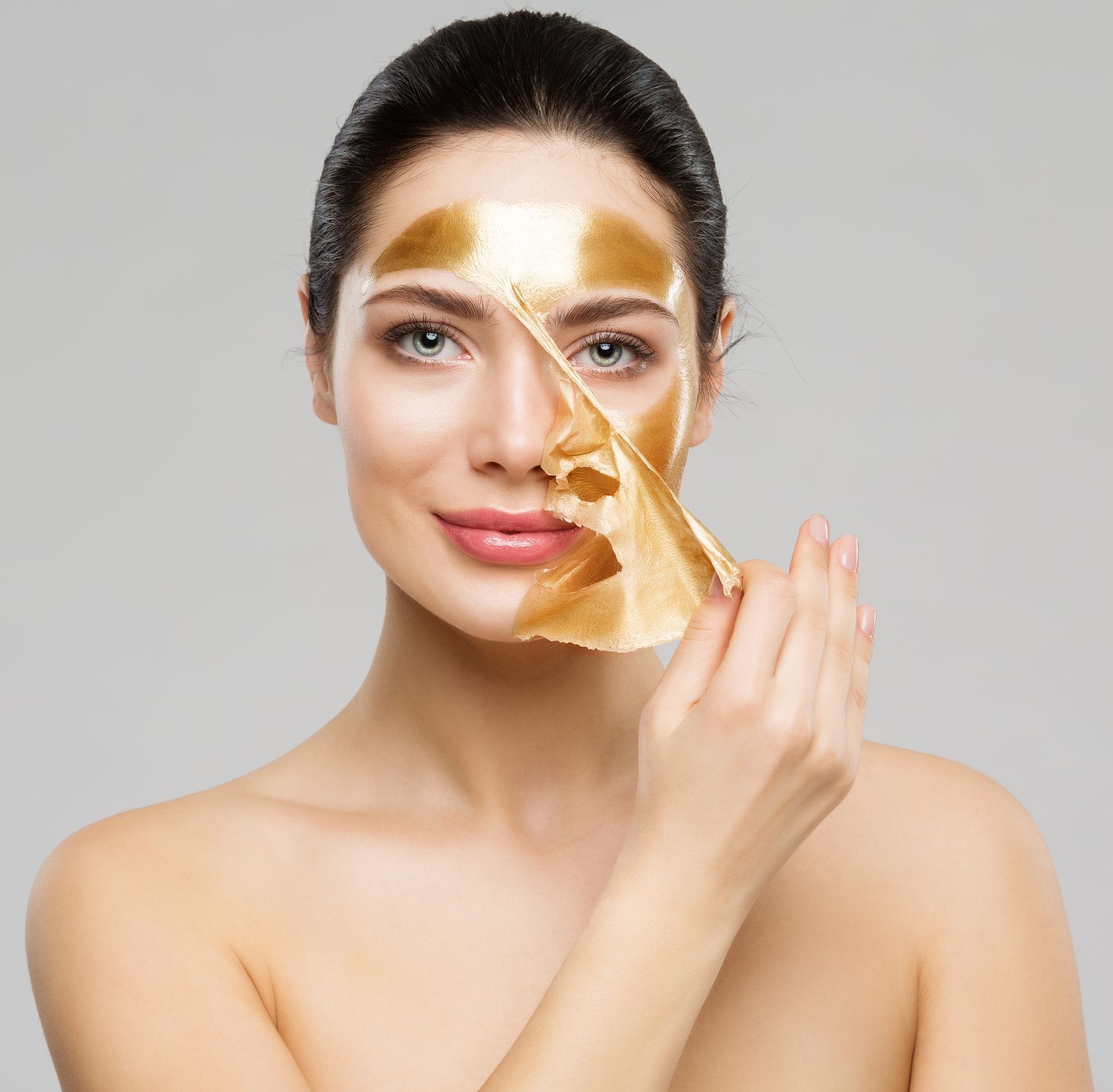 A woman is wearing a gold mask on her face.