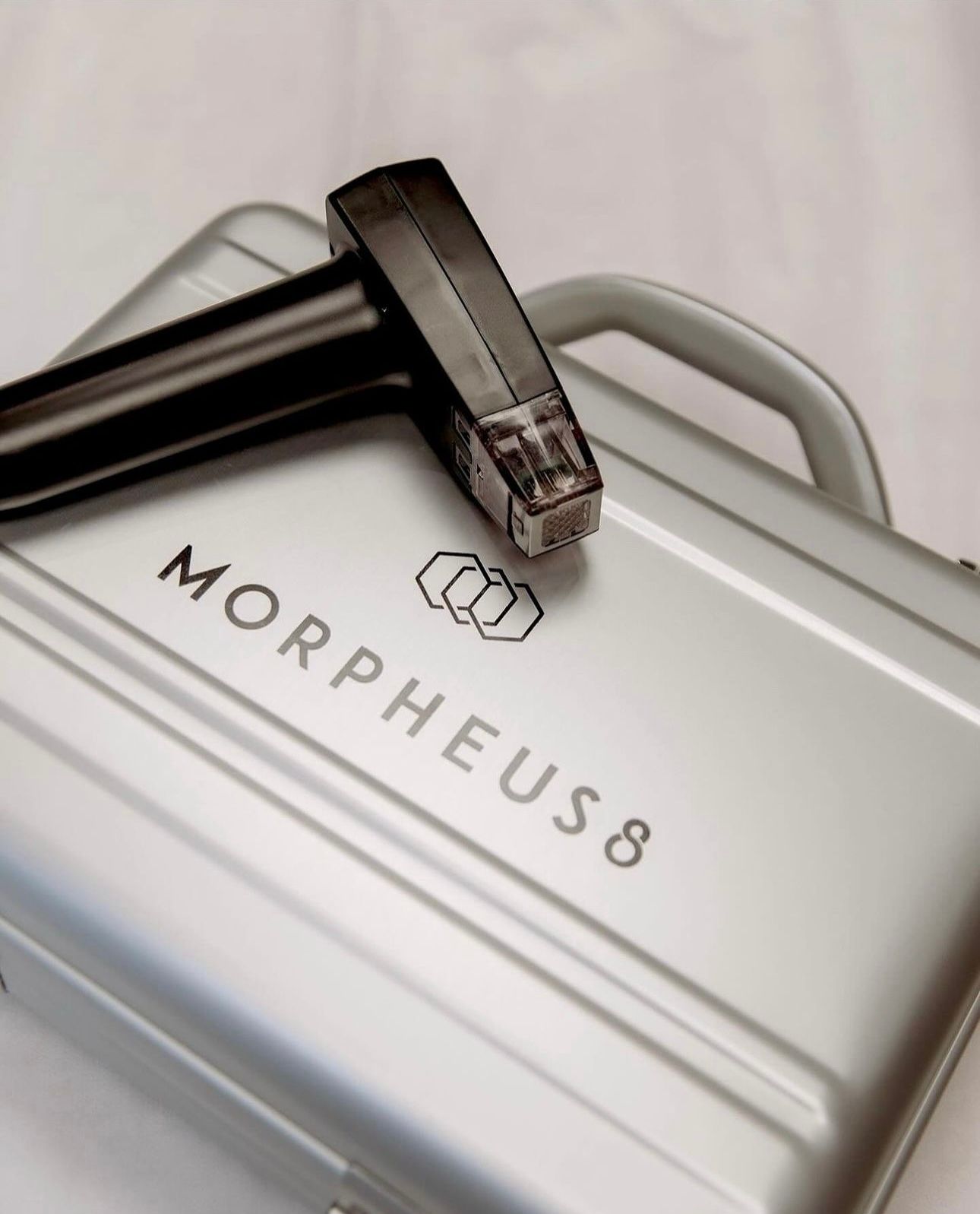 A silver morpheus 8 briefcase with a stapler on top of it