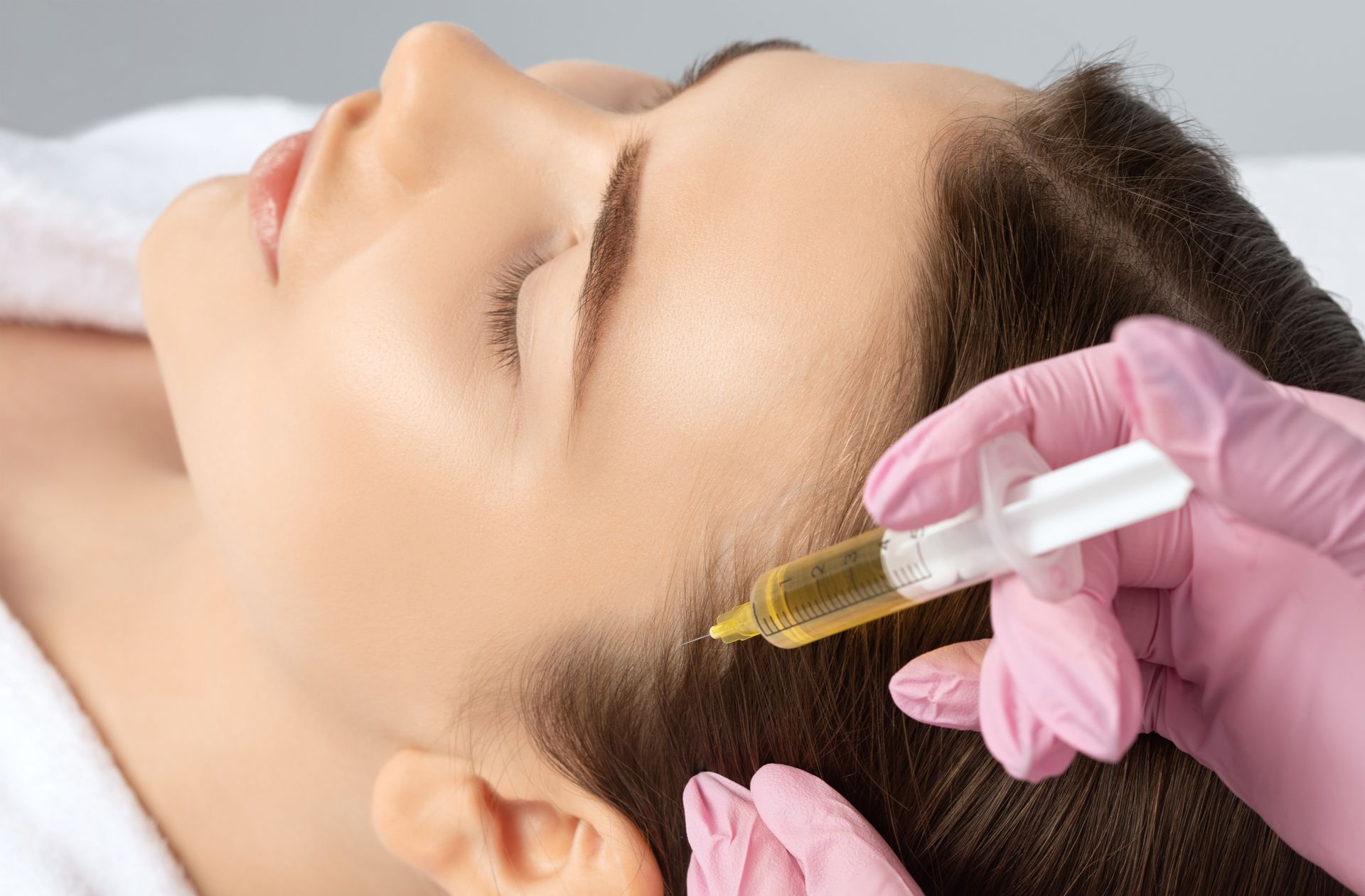 A woman is getting a botox injection in her forehead.