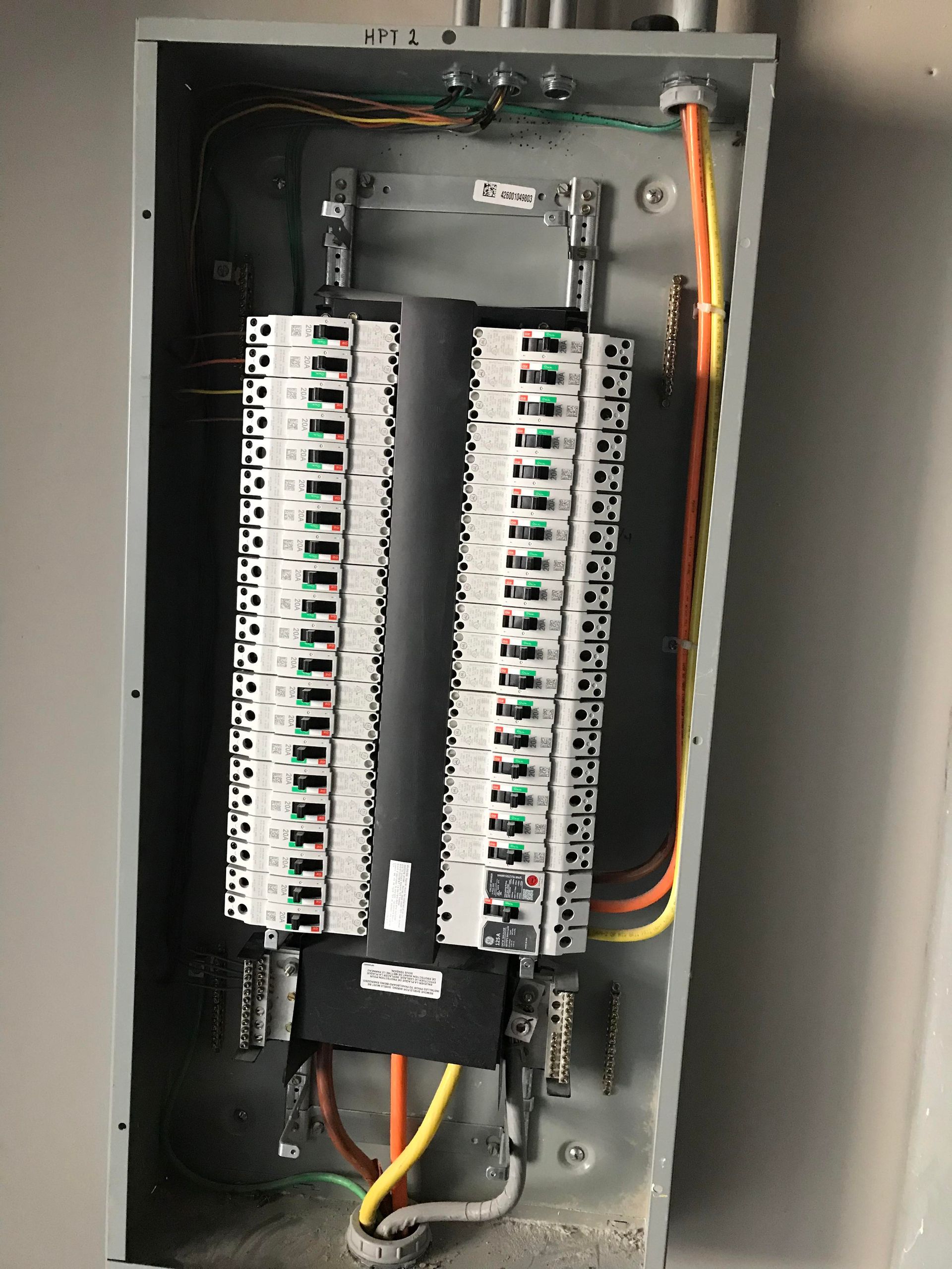 Electrical panel with rows of circuit breakers and colored wires within a metal enclosure.