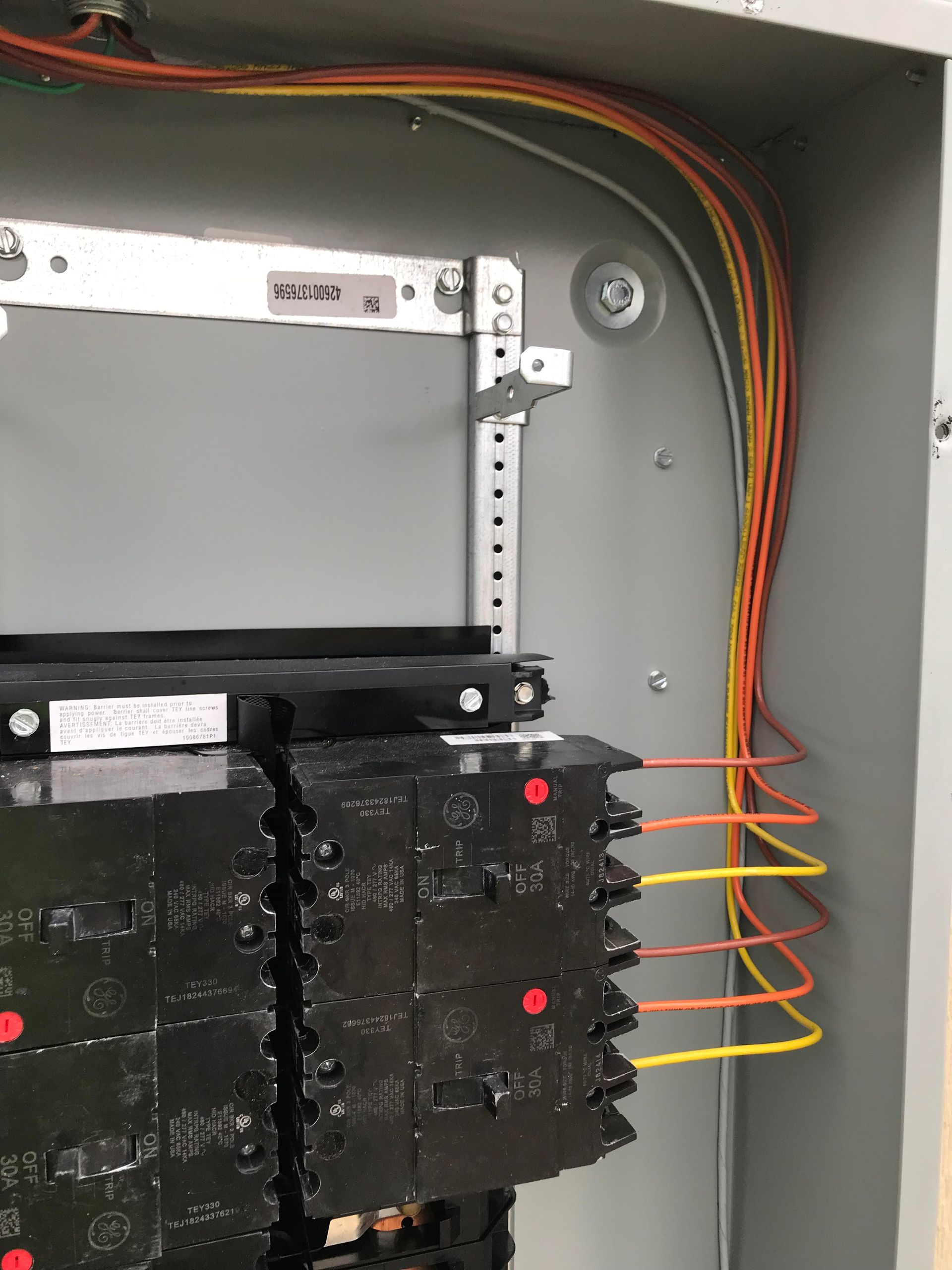 Electrical panel with orange, yellow, and gray wires connected to circuit breakers.