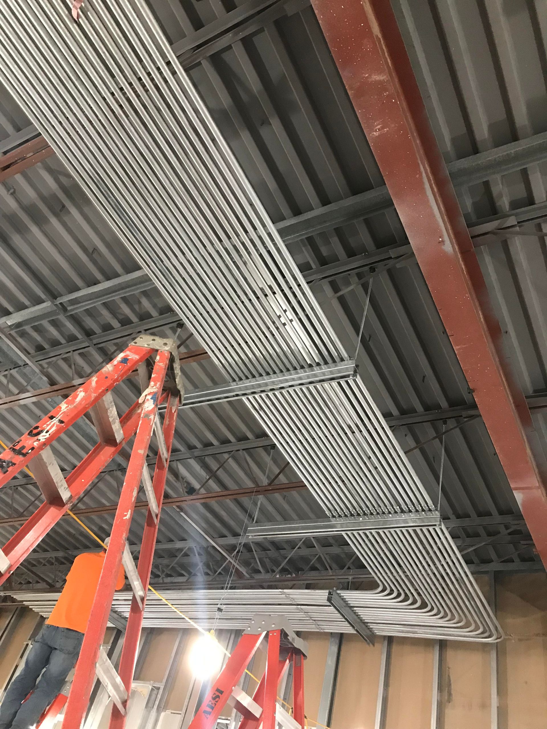 Metal conduit and ladder in an unfinished building, likely for electrical work.