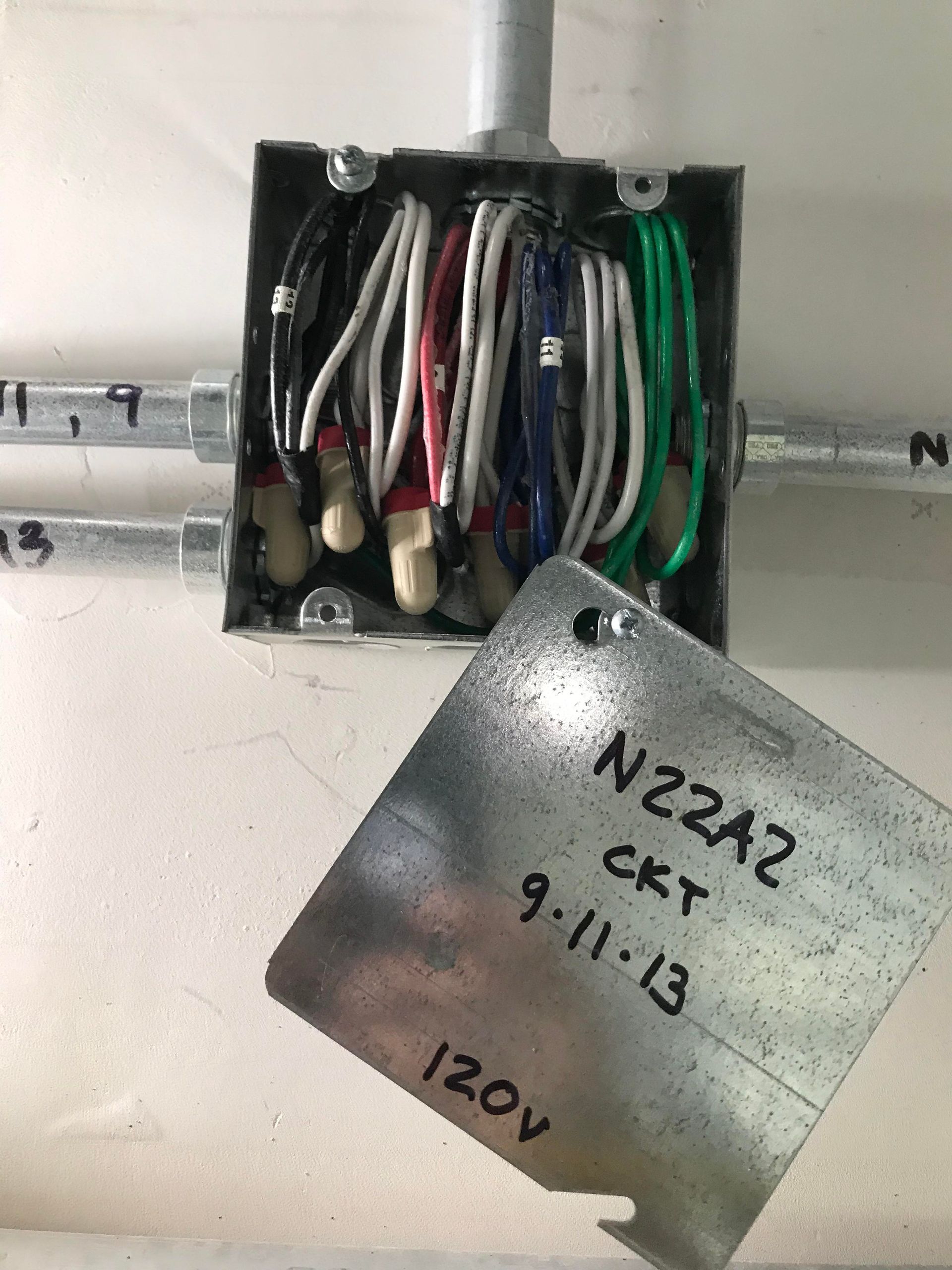 Electrical junction box with wires, metal tag labeled 