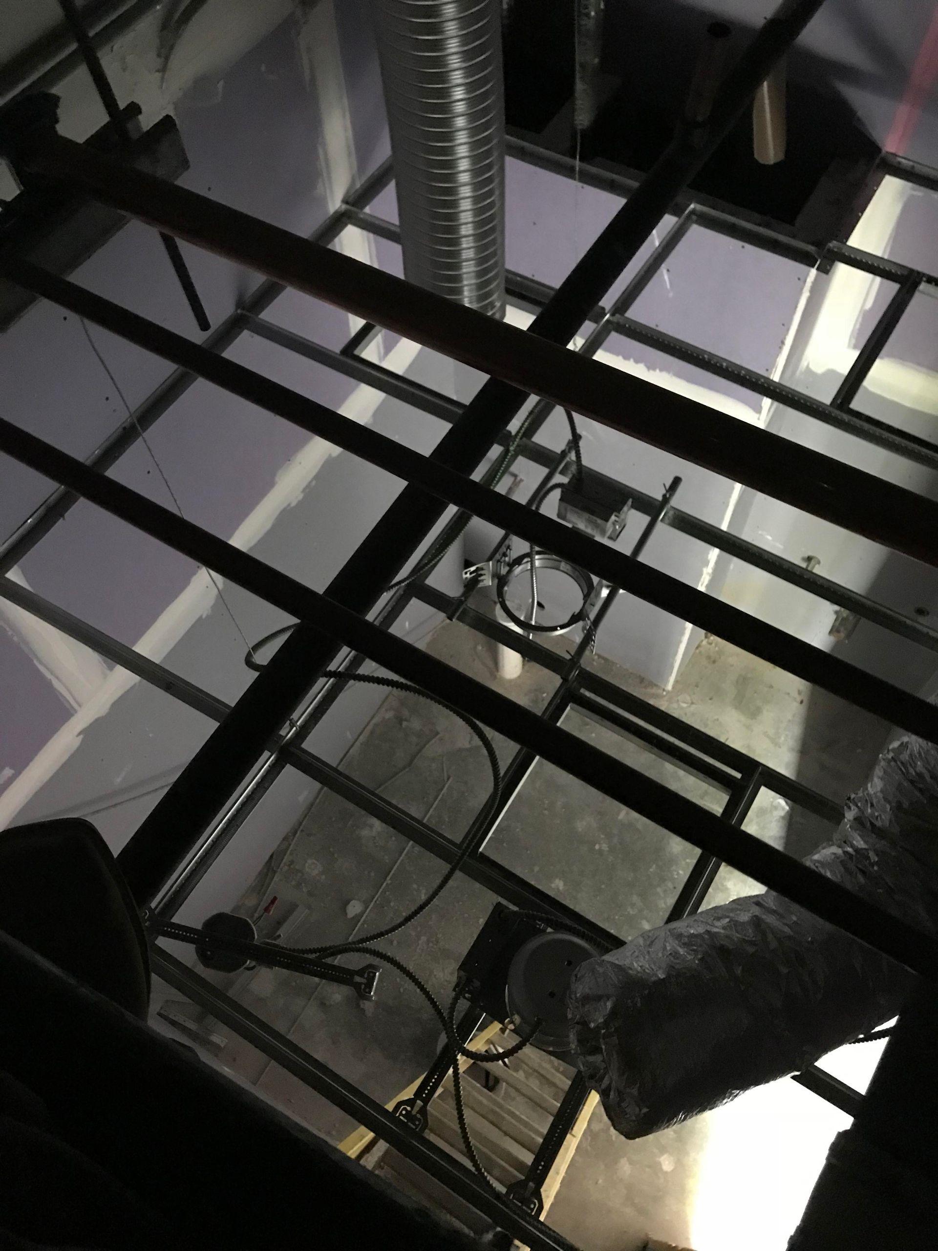 Overhead view of metal beams and ducts, possibly a ceiling. Black, silver, and gray colors.