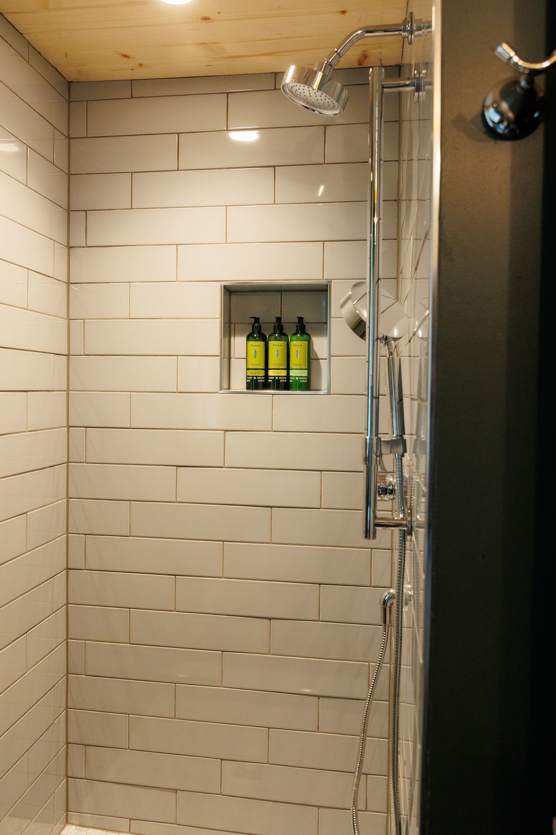 A shower with two bottles of soap in a niche.