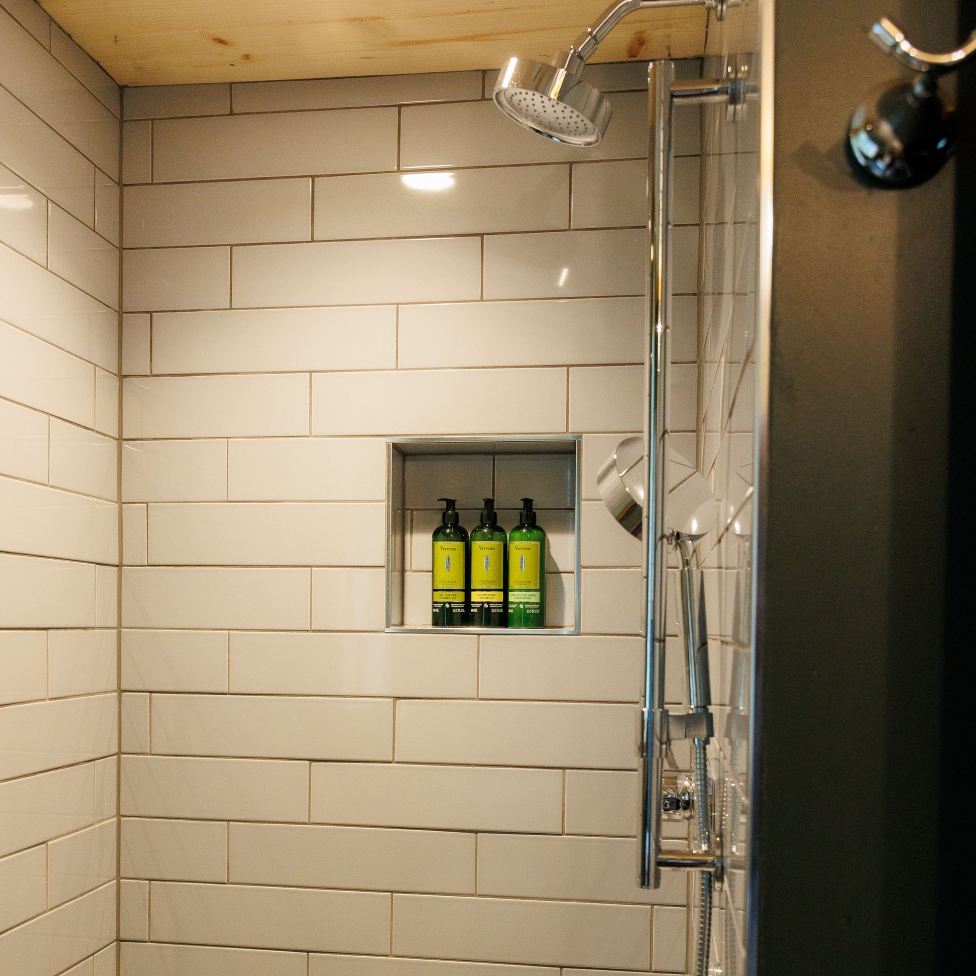 A shower with two bottles of soap in a niche.