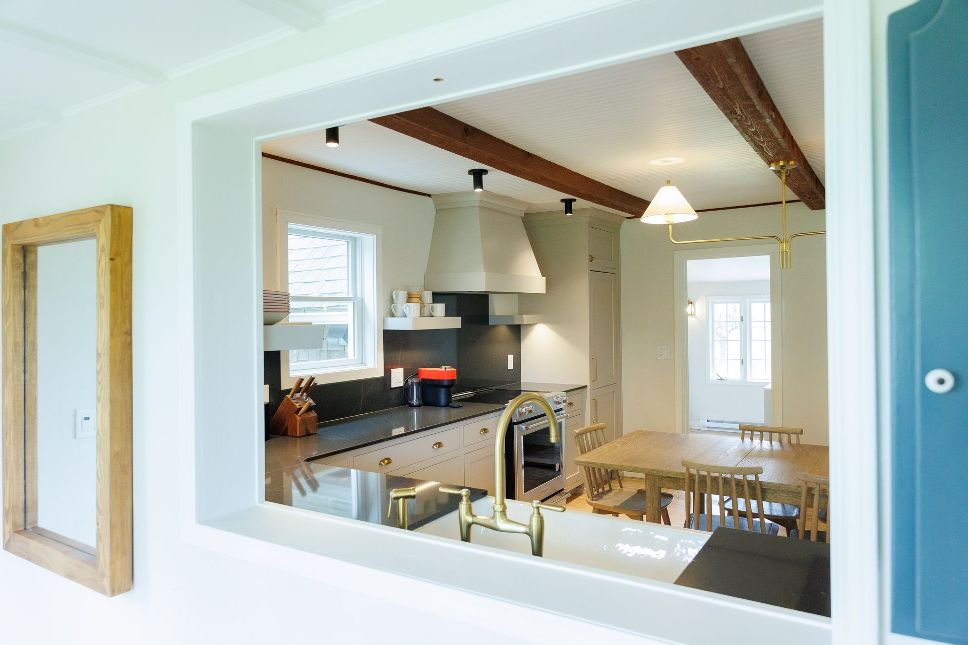 A kitchen with a table and chairs through a window.