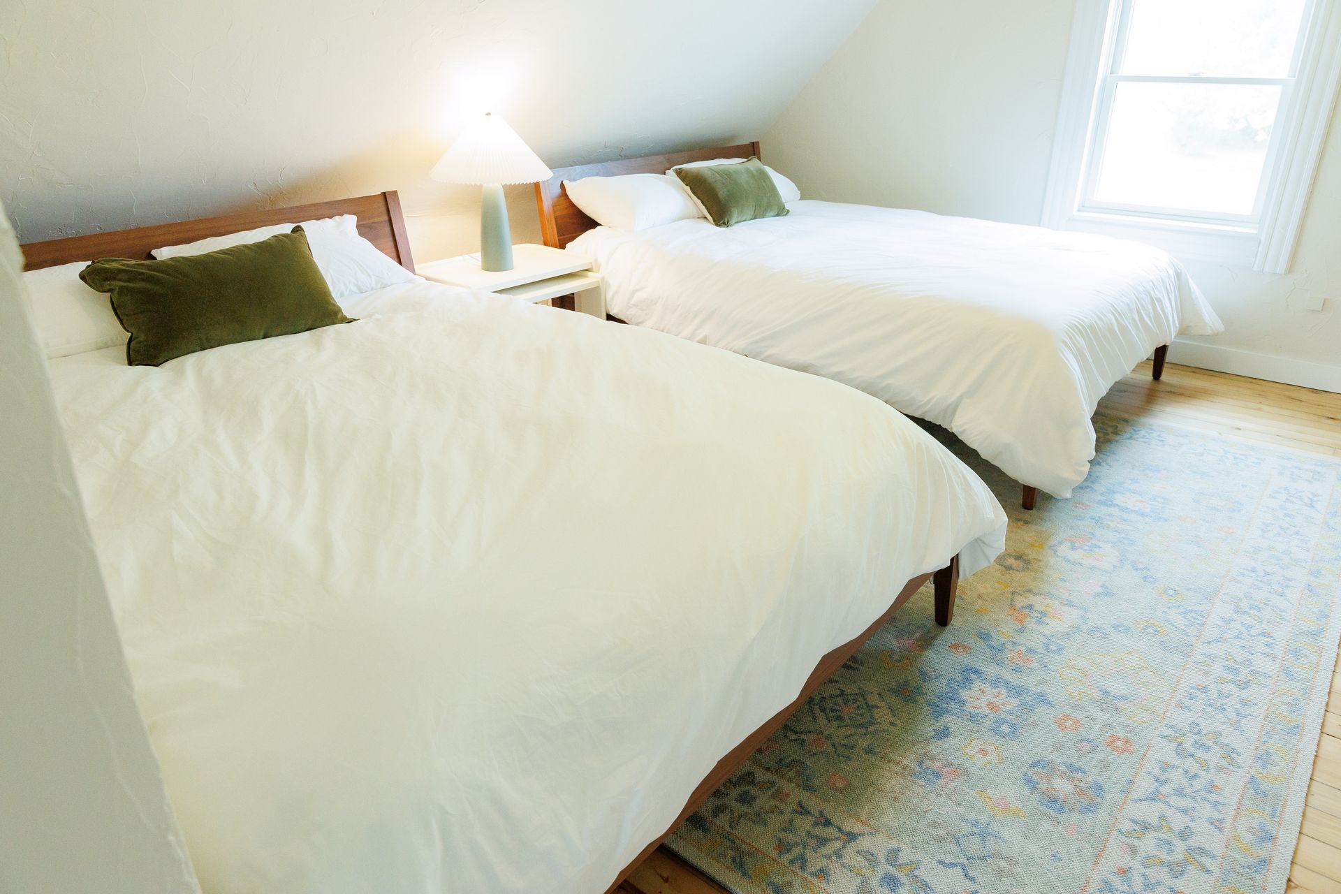 A bedroom with two beds and a rug on the floor