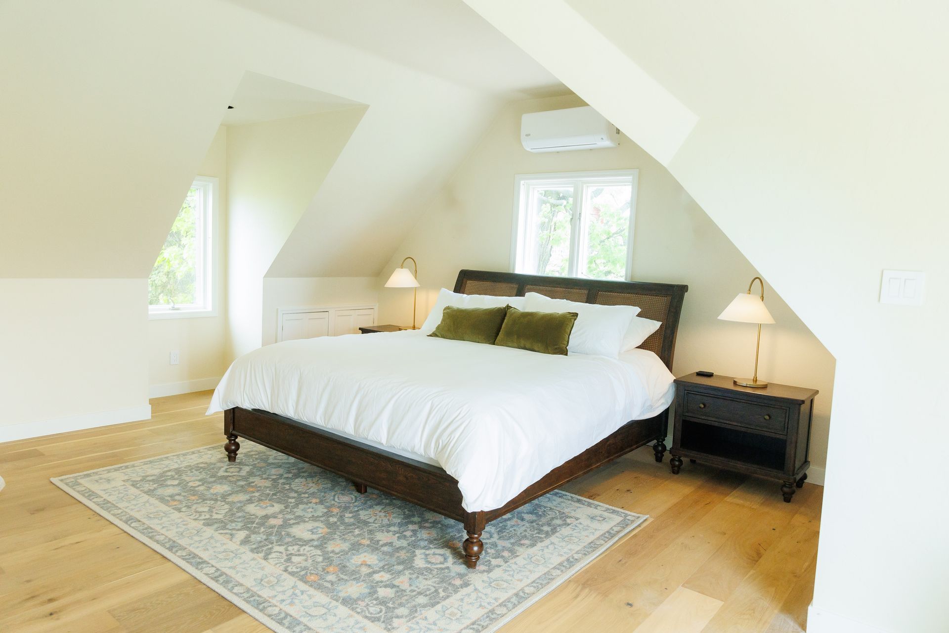 A bedroom with a king size bed and a rug on the floor.