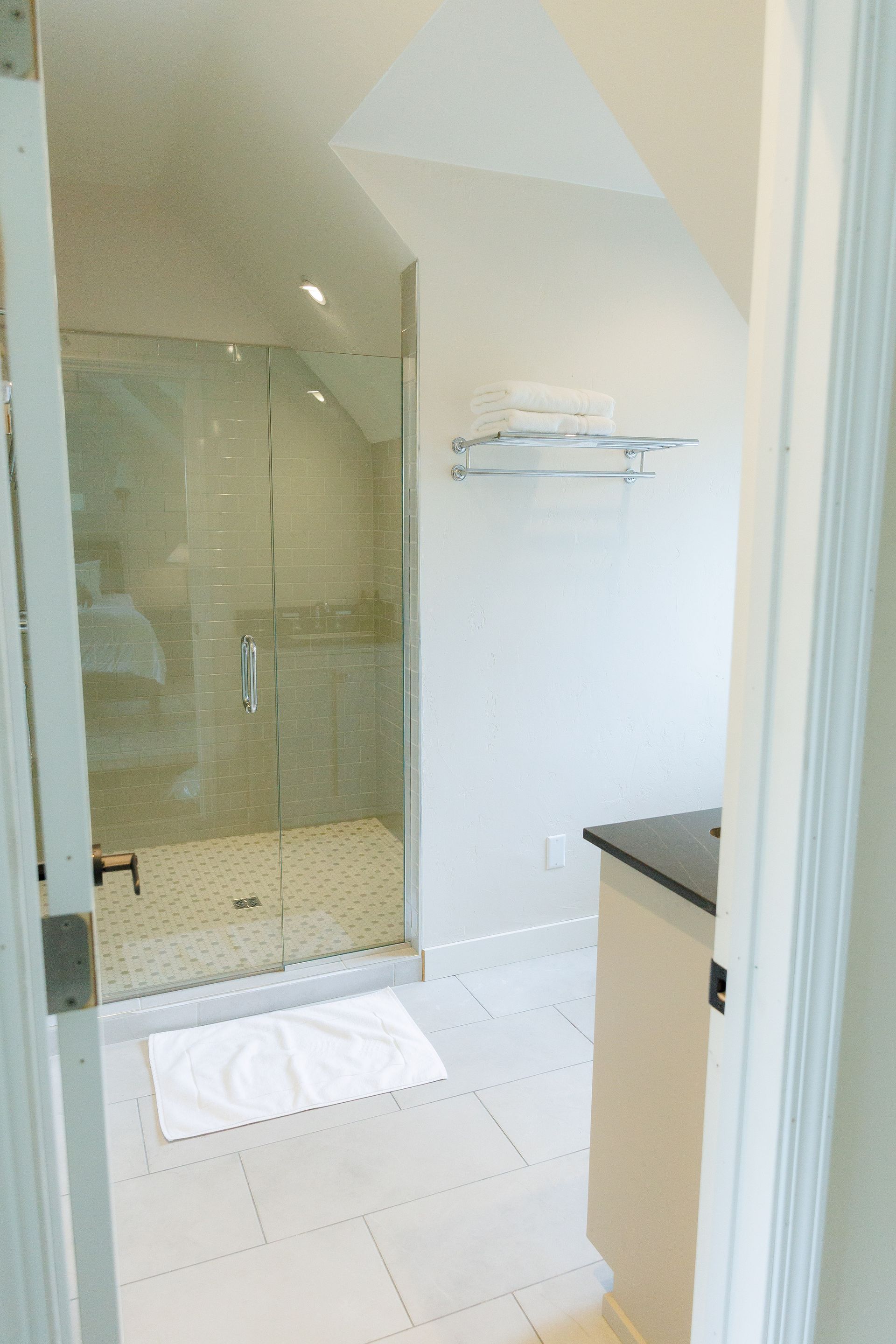 A bathroom with a walk in shower and a white towel on the floor.