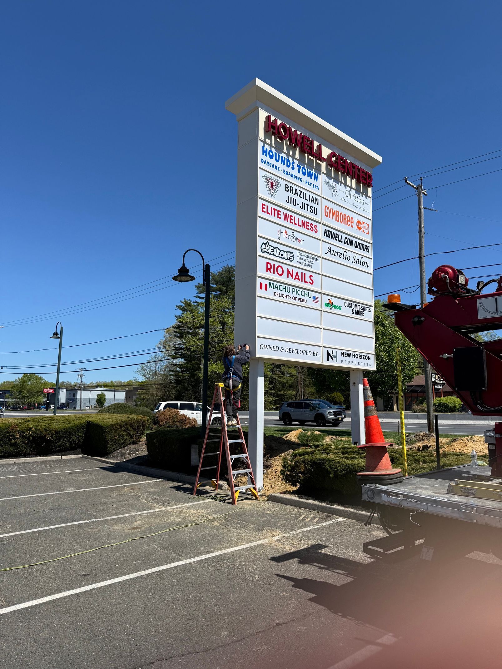 Tall roadside sign with Japanese text beside a parking lot under a clear blue sky