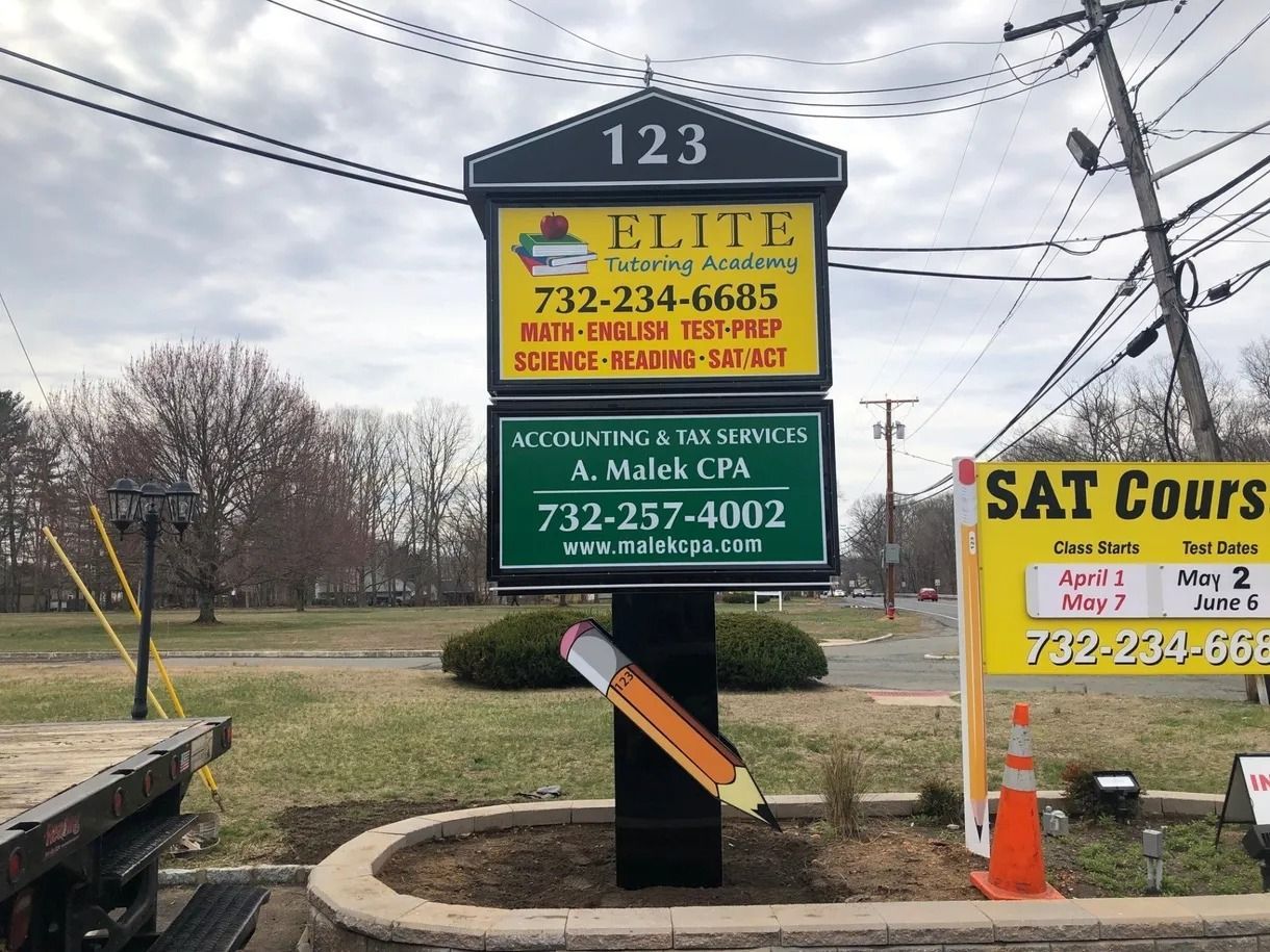Roadside business signs for tax, auto, and SAT courses beside a utility pole and traffic cone.