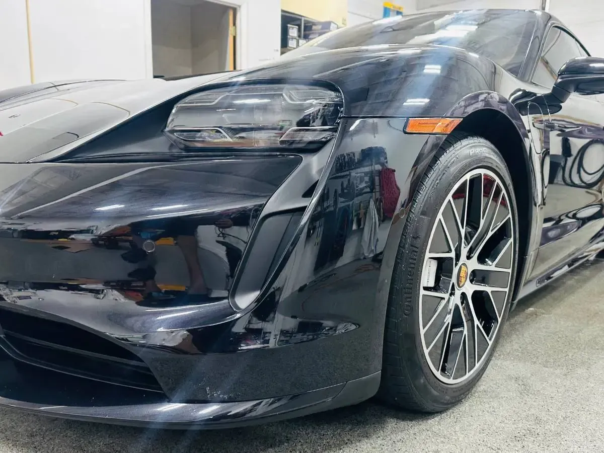 A black sports car is parked in a garage.