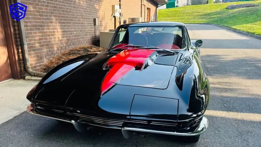 A black and red corvette is parked in front of a brick building