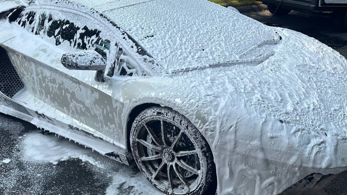 A white lamborghini aventador is covered in foam.